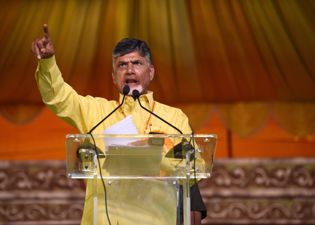 Chandrababu speaking at a political rally, addressing the crowd and gesturing with his hand.
