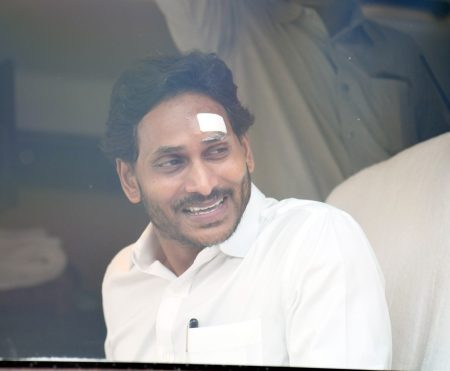 YS Jagan Mohan Reddy addressing a crowd during his election campaign, surrounded by security personnel.